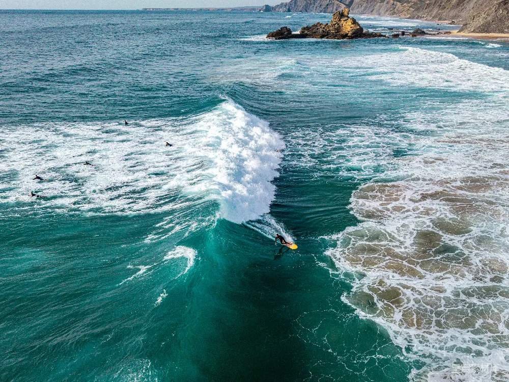 高清摄影  一个冲浪者在岩石海岸线附近驾驭着巨大的海浪。
