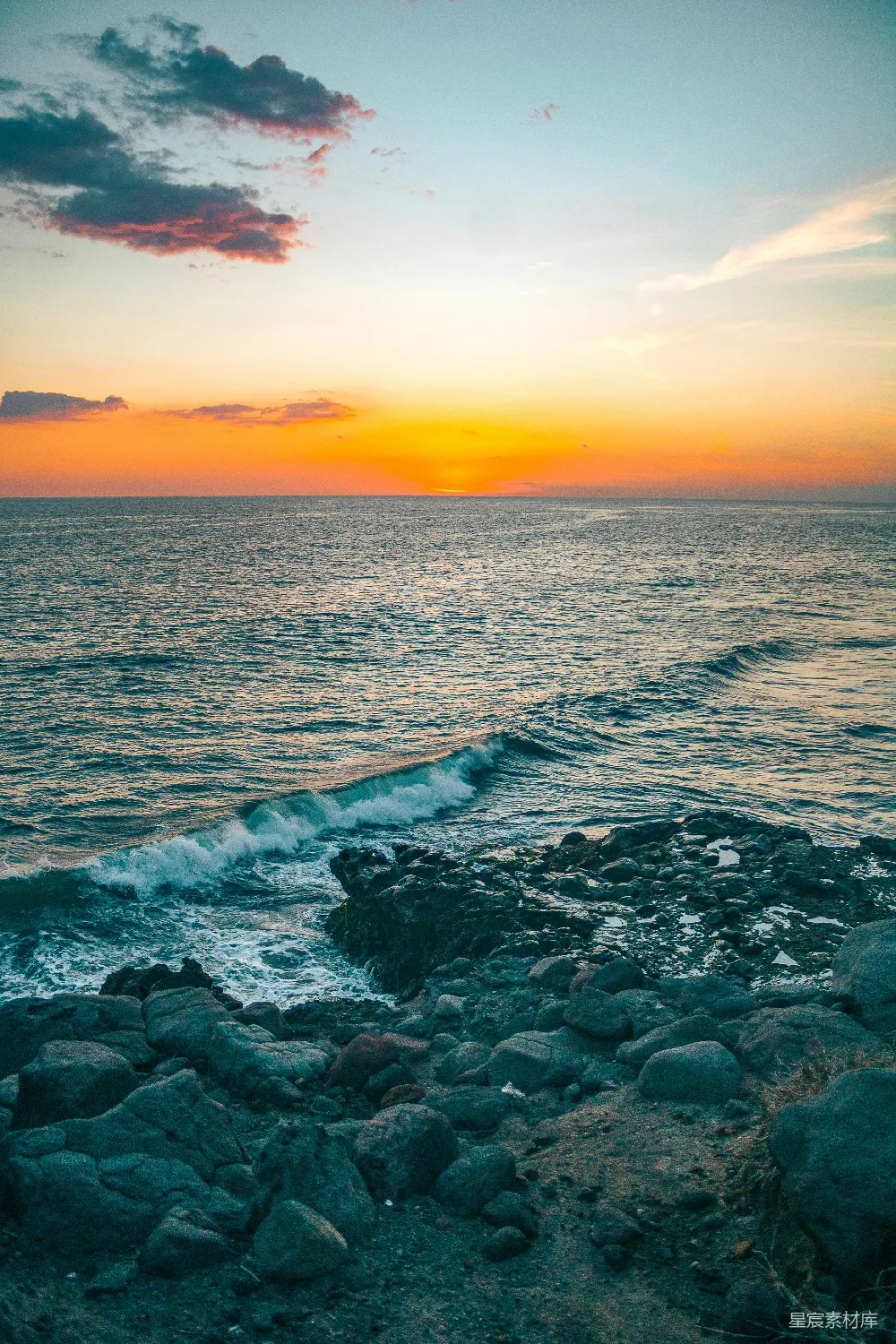 高清摄影  夕阳映照在海面上，岩石海岸线清晰可见。