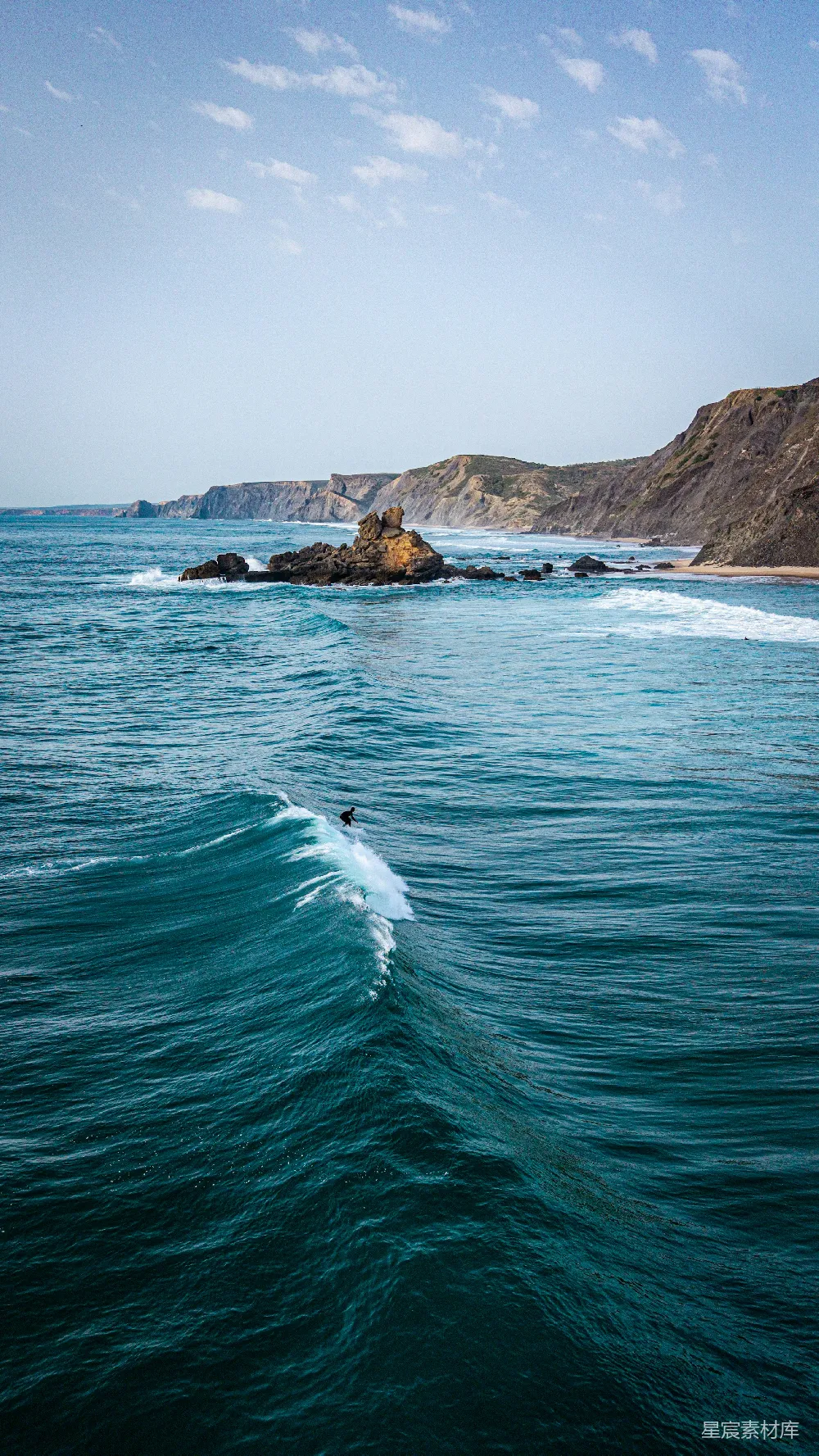 高清摄影  一个冲浪者在崎岖的海岸线附近冲浪。