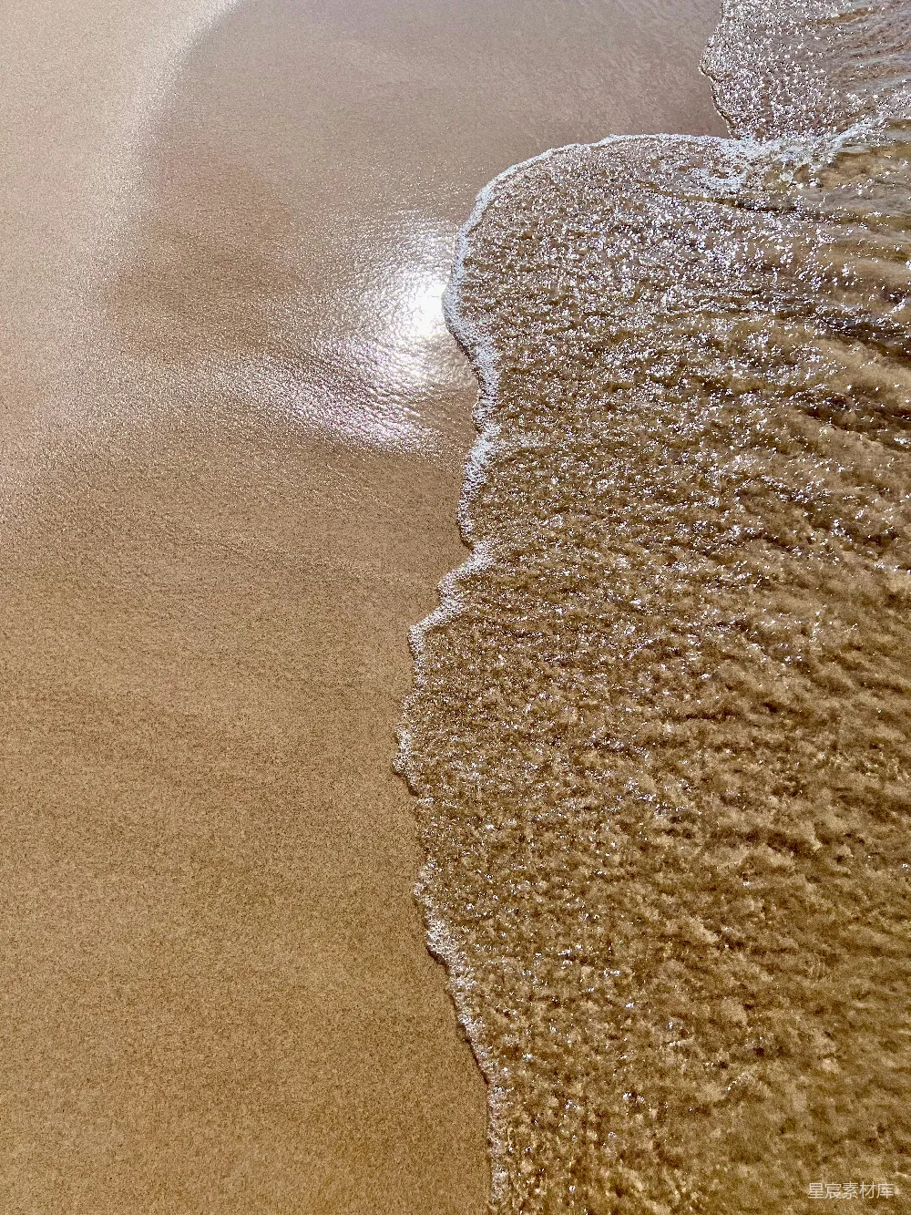 高清摄影  海滩上湿沙上轻轻的波浪。
