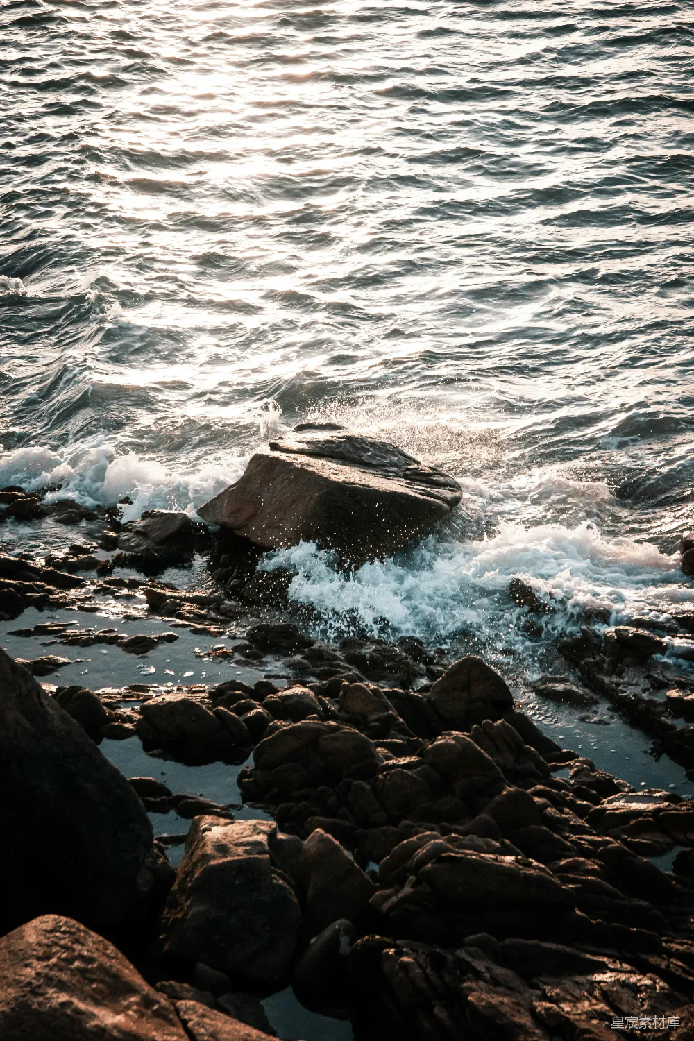 高清摄影  白天时棕色的岩石海岸，海浪拍打着岩石。