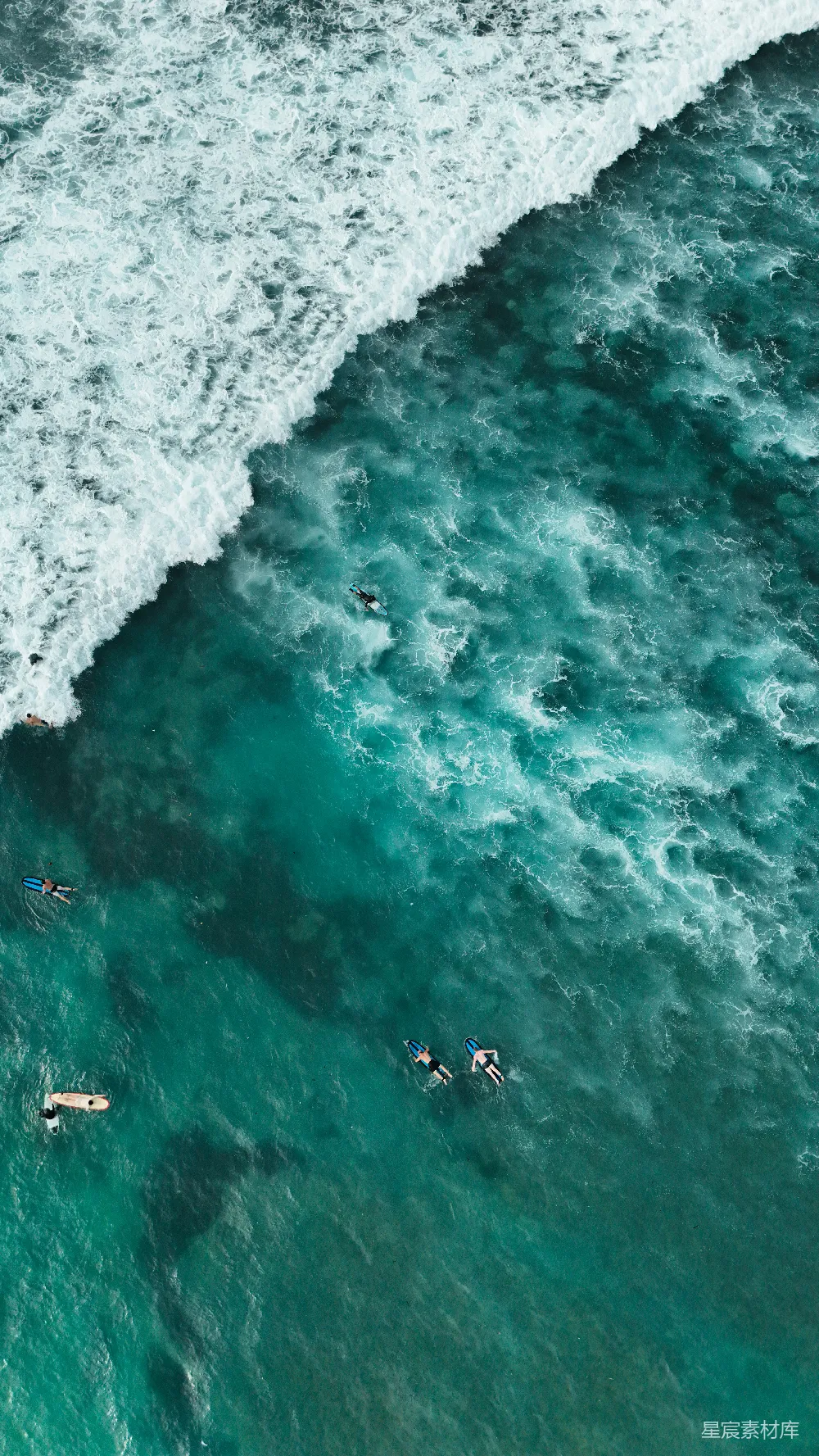 高清摄影  冲浪者在碧绿色的海水中漂浮，海浪正在破碎。