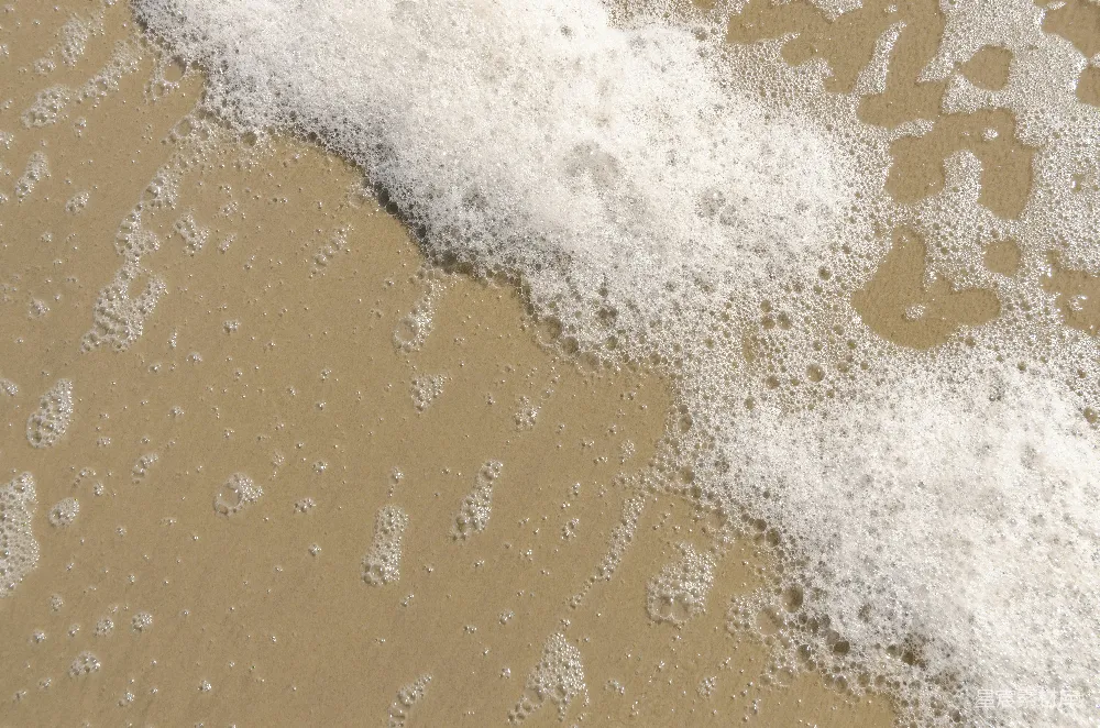 高清摄影  白色的海浪拍打着棕色的沙滩。