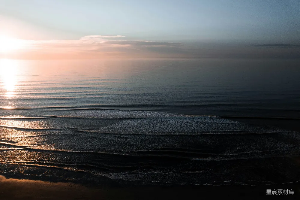 高清摄影  夕阳正缓缓落向海面，海滩上一片宁静。