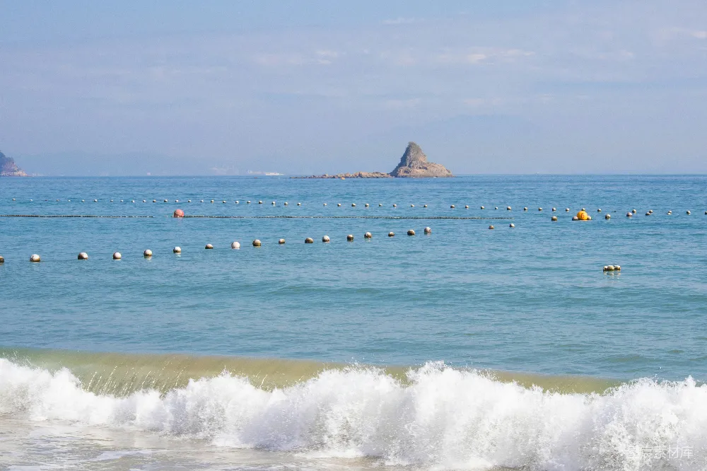高清摄影  海浪拍打着沙滩，海中漂浮着浮标。