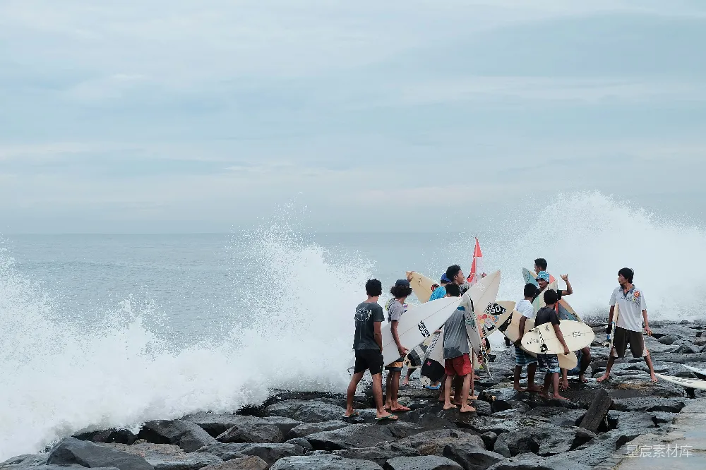 高清摄影  冲浪者在岩石海岸上拿着冲浪板观看海浪