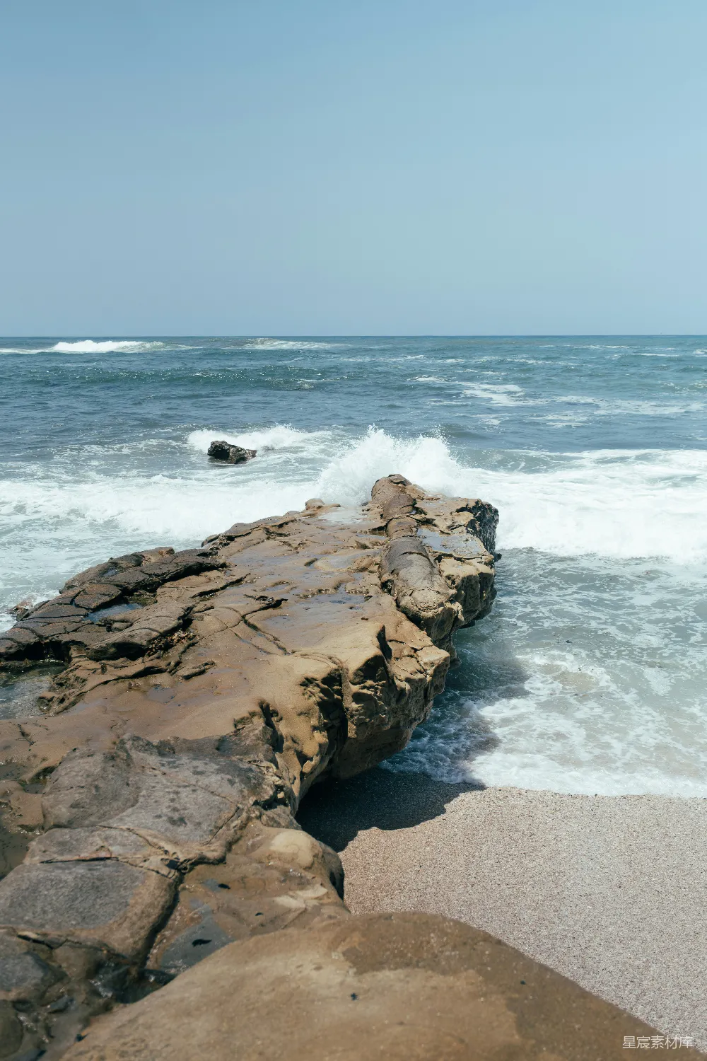 高清摄影  海浪拍打着岩石海岸，在晴朗的天空下。
