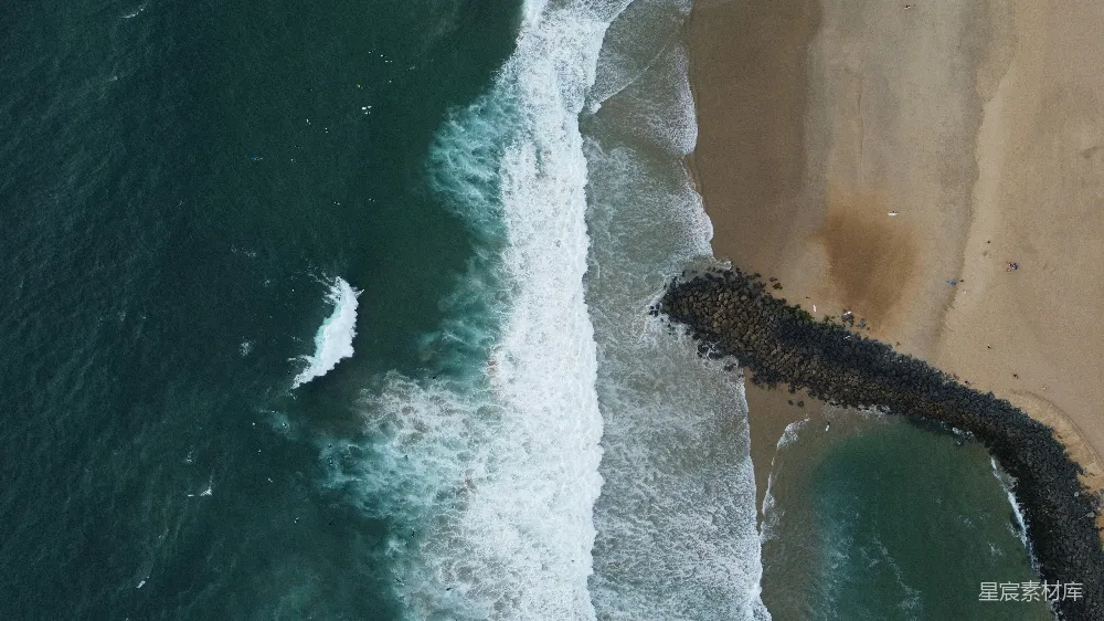 高清摄影  海浪拍打着沙滩，岩石屏障在前景。