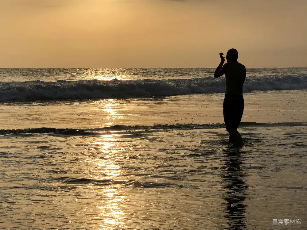高清摄影  女人站在海滩上的剪影，夕阳西下。