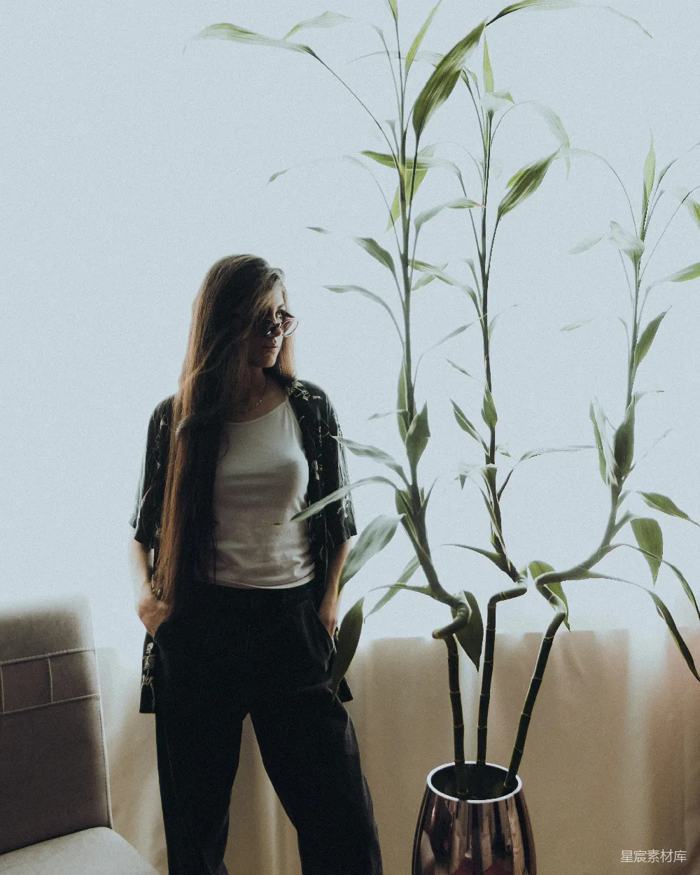 高清摄影  一个女人站在房间里的植物旁边。
