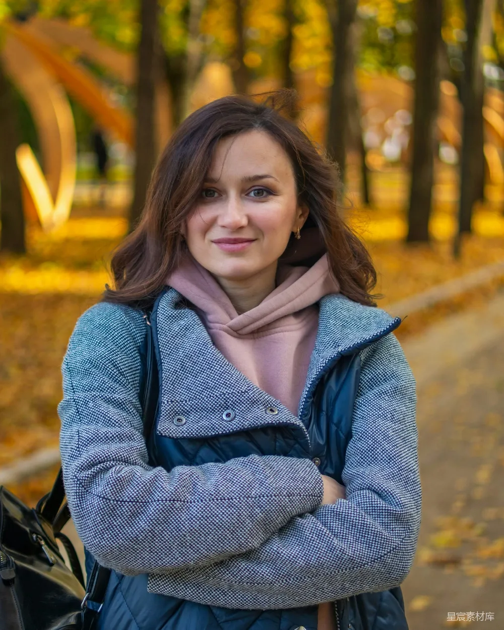 高清摄影  一个女人站在公园里，双臂交叉。