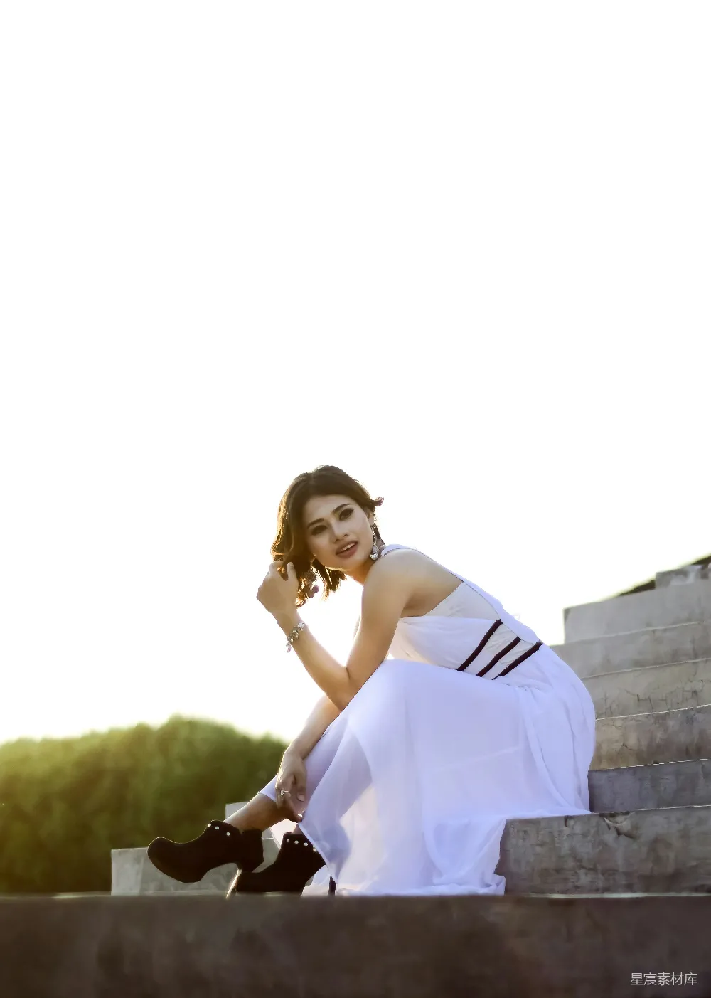 高清摄影  穿着黄色连衣裙的女子坐在混凝土墙上，白天的场景。