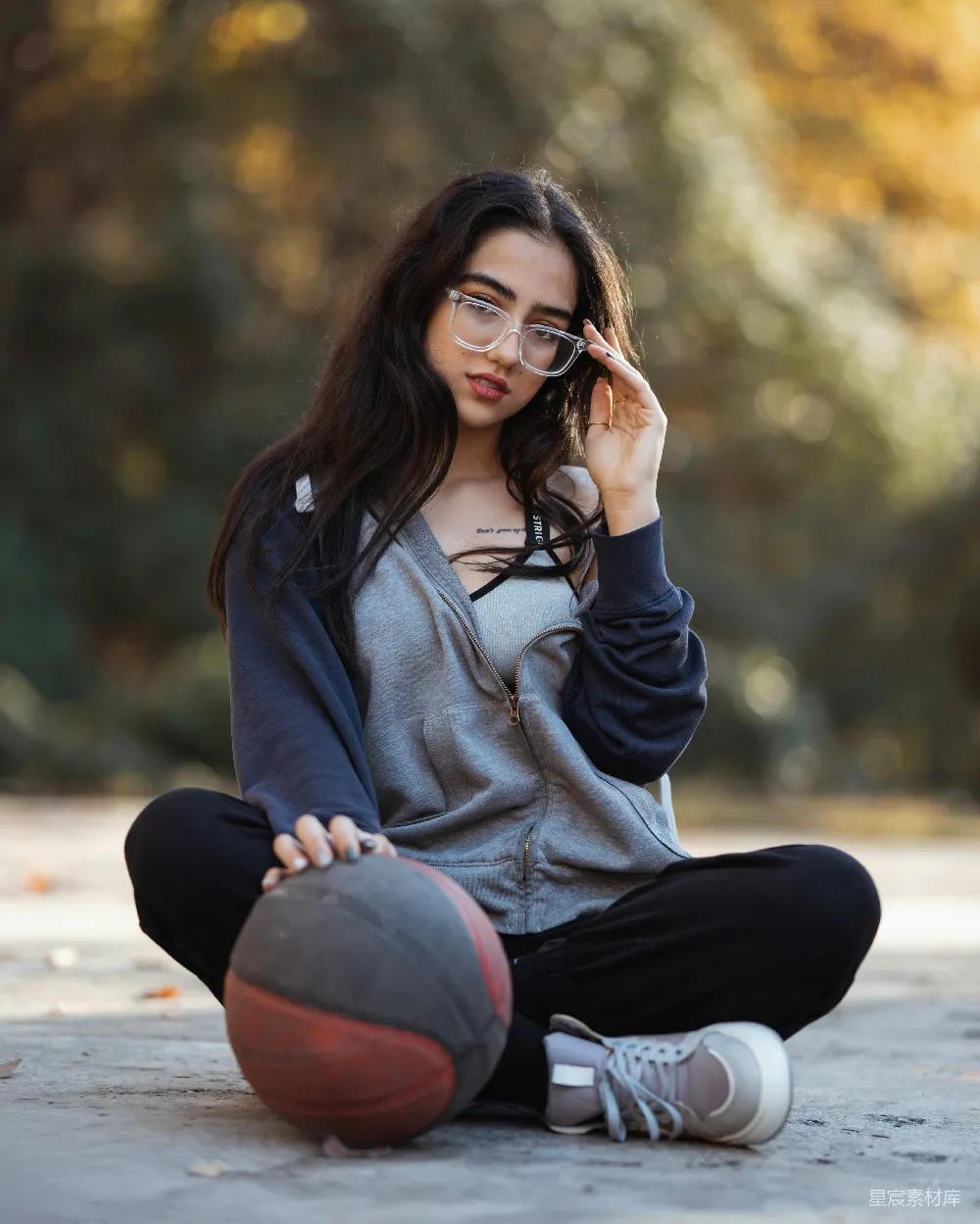 高清摄影  年轻的女孩坐在那里，手里拿着篮球，戴着眼镜。