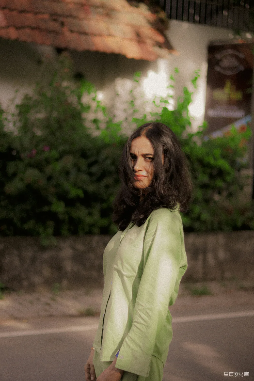 高清摄影  一位穿着浅绿色衣服的女人站在户外。