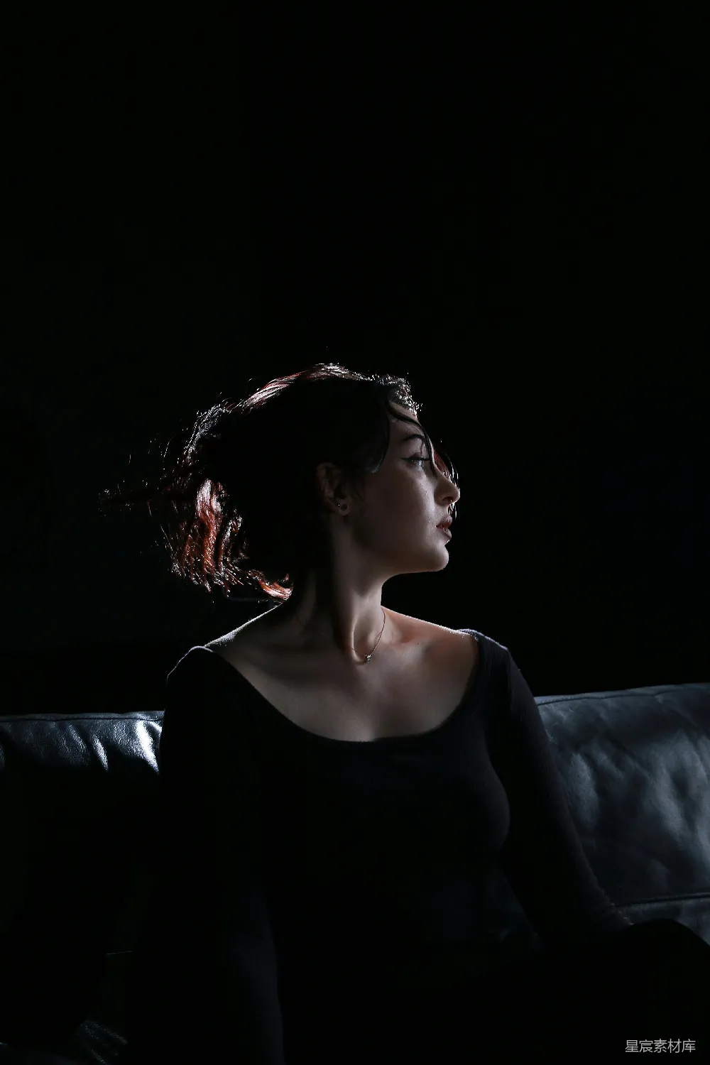 高清摄影  一个女人在黑暗中坐在沙发上。