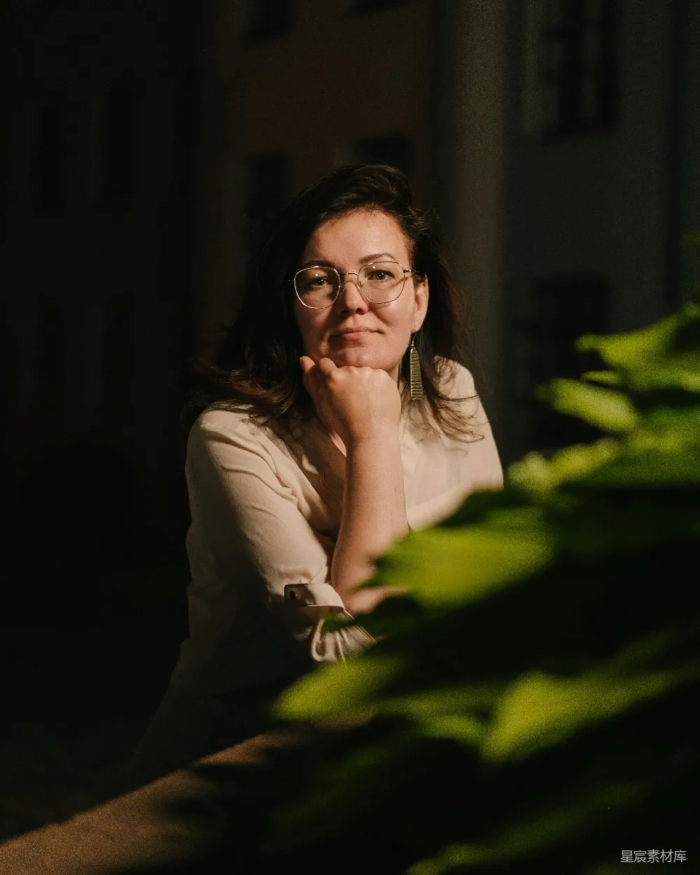 高清摄影  戴眼镜的女人坐在一盆植物前面。