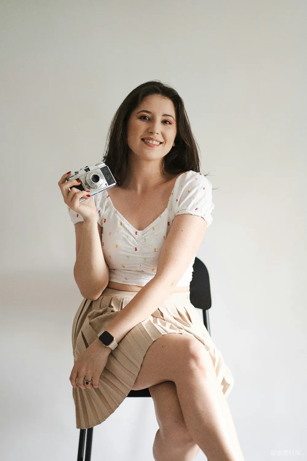 高清摄影  一个女人坐在椅子上拿着相机。