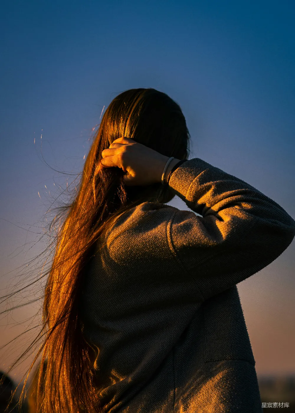 高清摄影 人物 一个女人站在夕阳下，整理着她的头发。