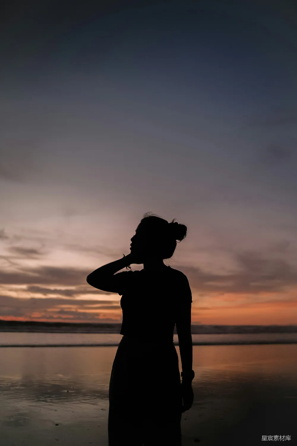 高清摄影  一个女人站在海滩上，靠近海洋。
