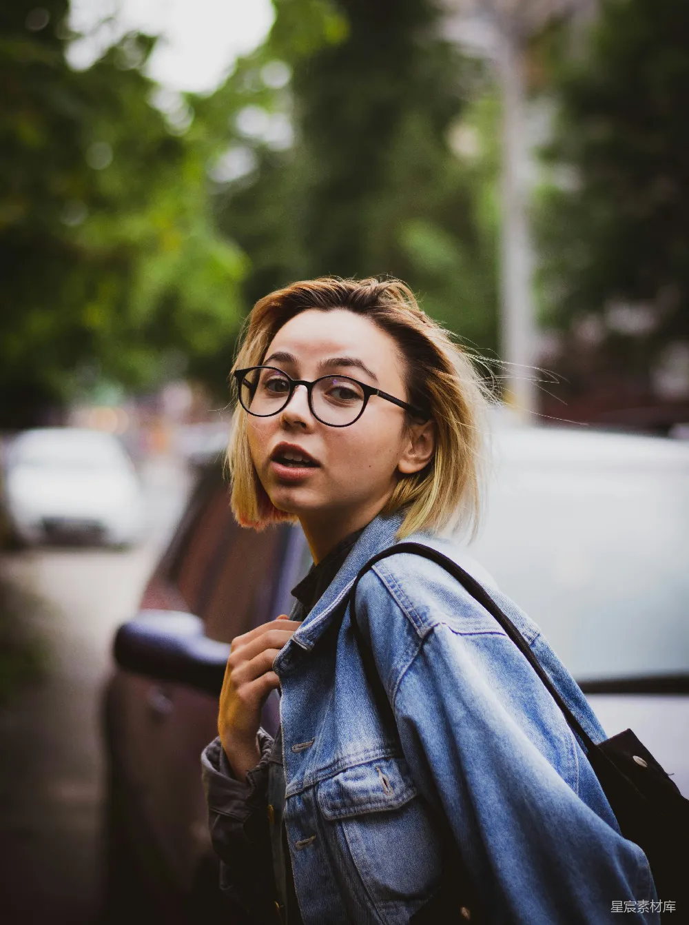 高清摄影  穿着蓝色牛仔夹克，戴着黑色框架眼镜的女人