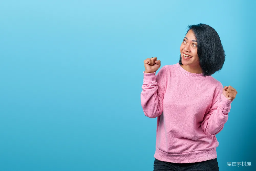 高清摄影  一个穿着粉红色毛衣的女人正在摆姿势拍照。