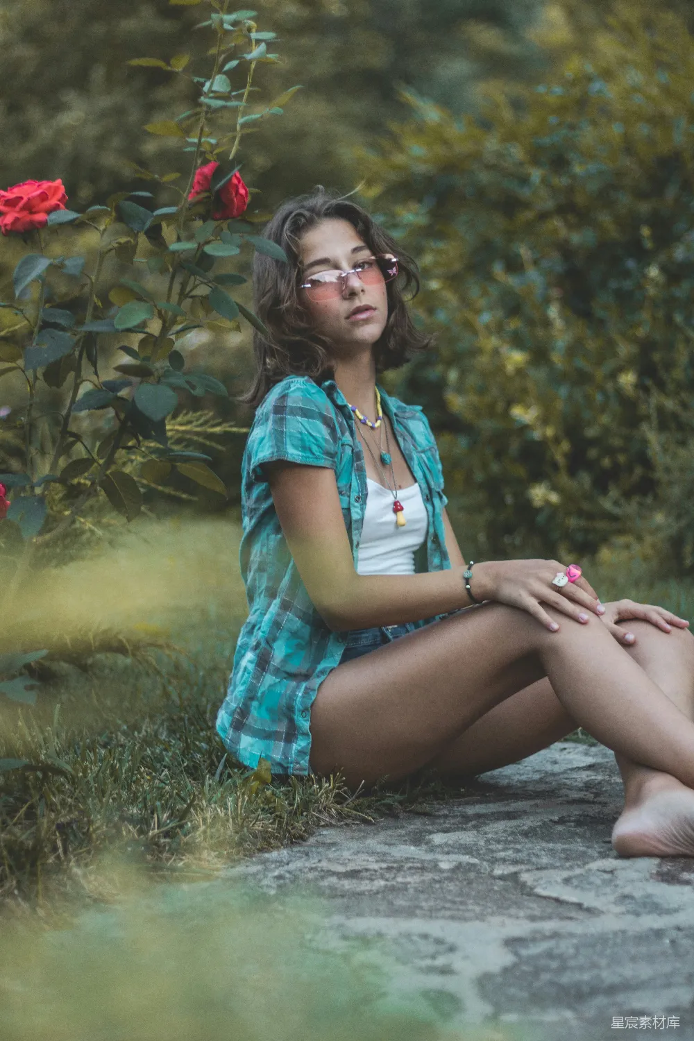 高清摄影 人物 一位女子坐在玫瑰花丛前的地上。