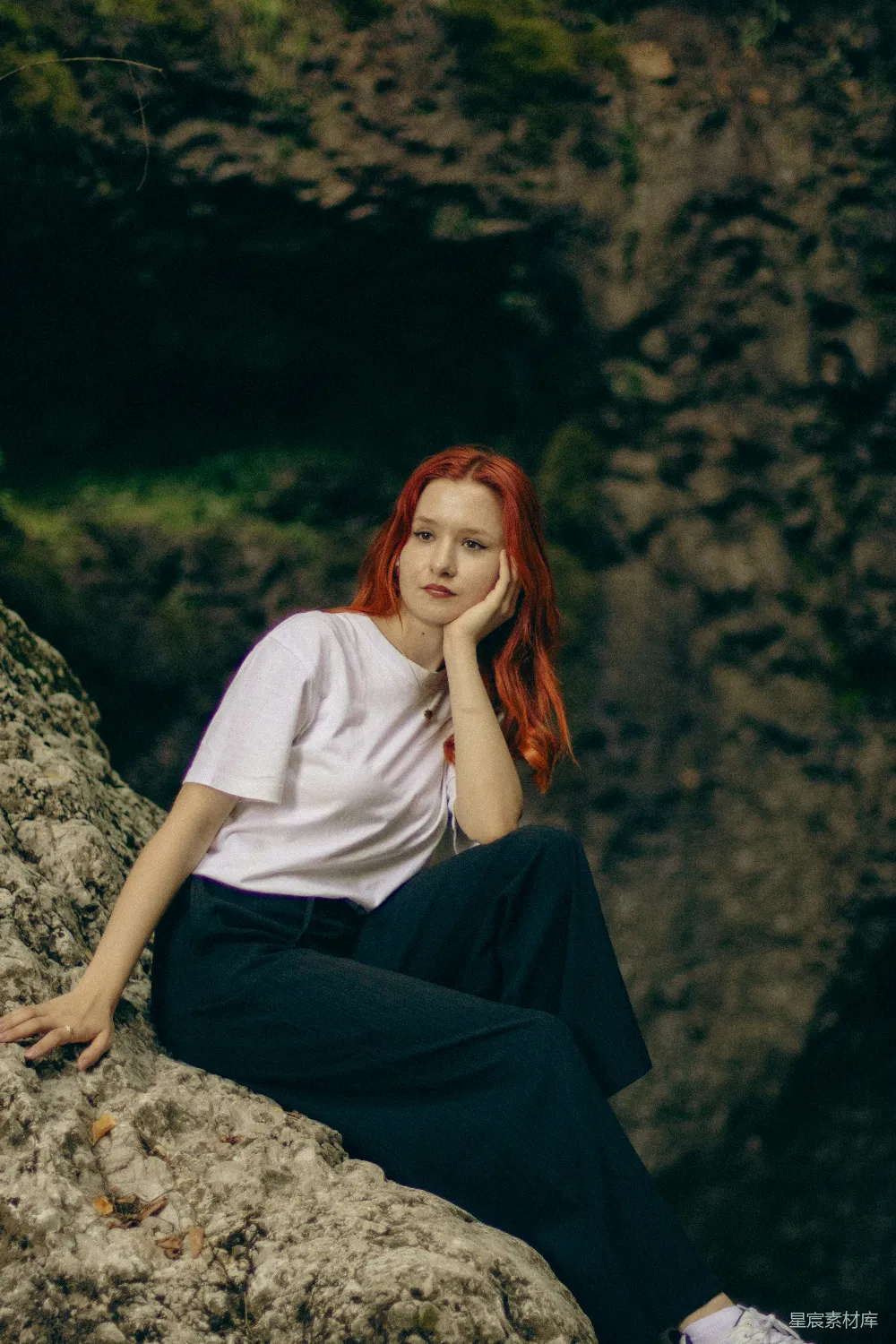 高清摄影  一个红发的女人坐在岩石上。