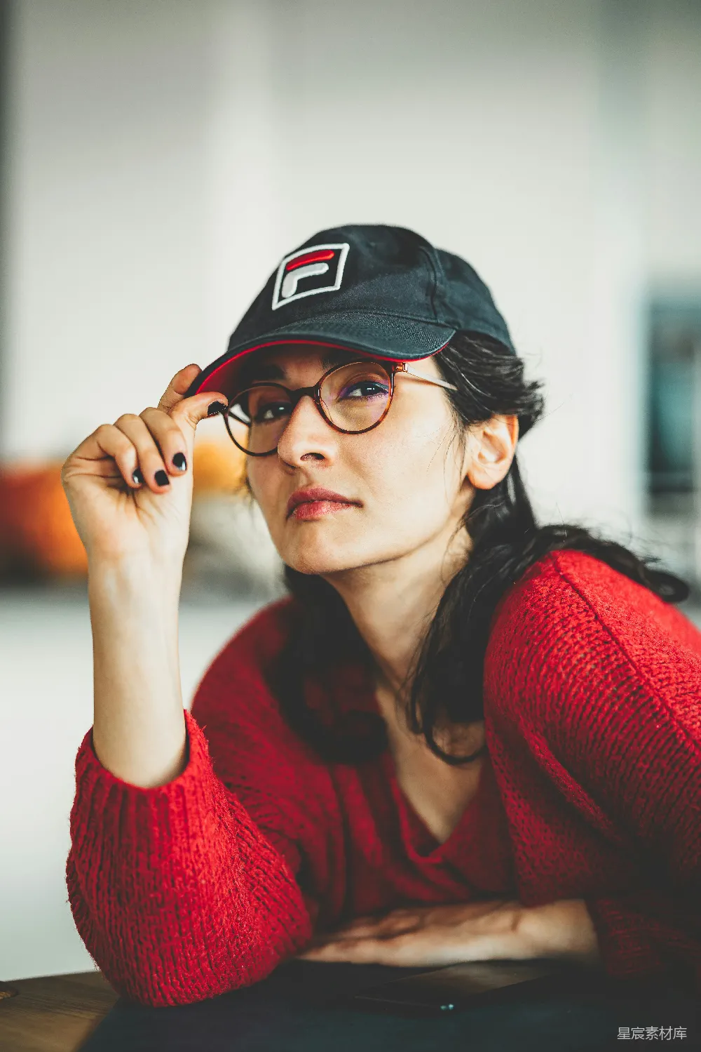 高清摄影 人物 一个戴着帽子和眼镜的女人坐在桌子旁。