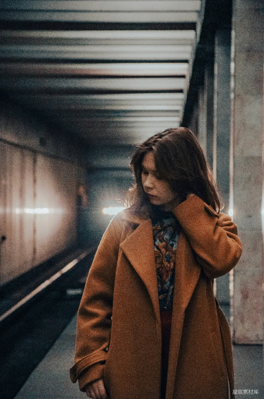 高清摄影  一个女人站在地铁站里，手放在头上。