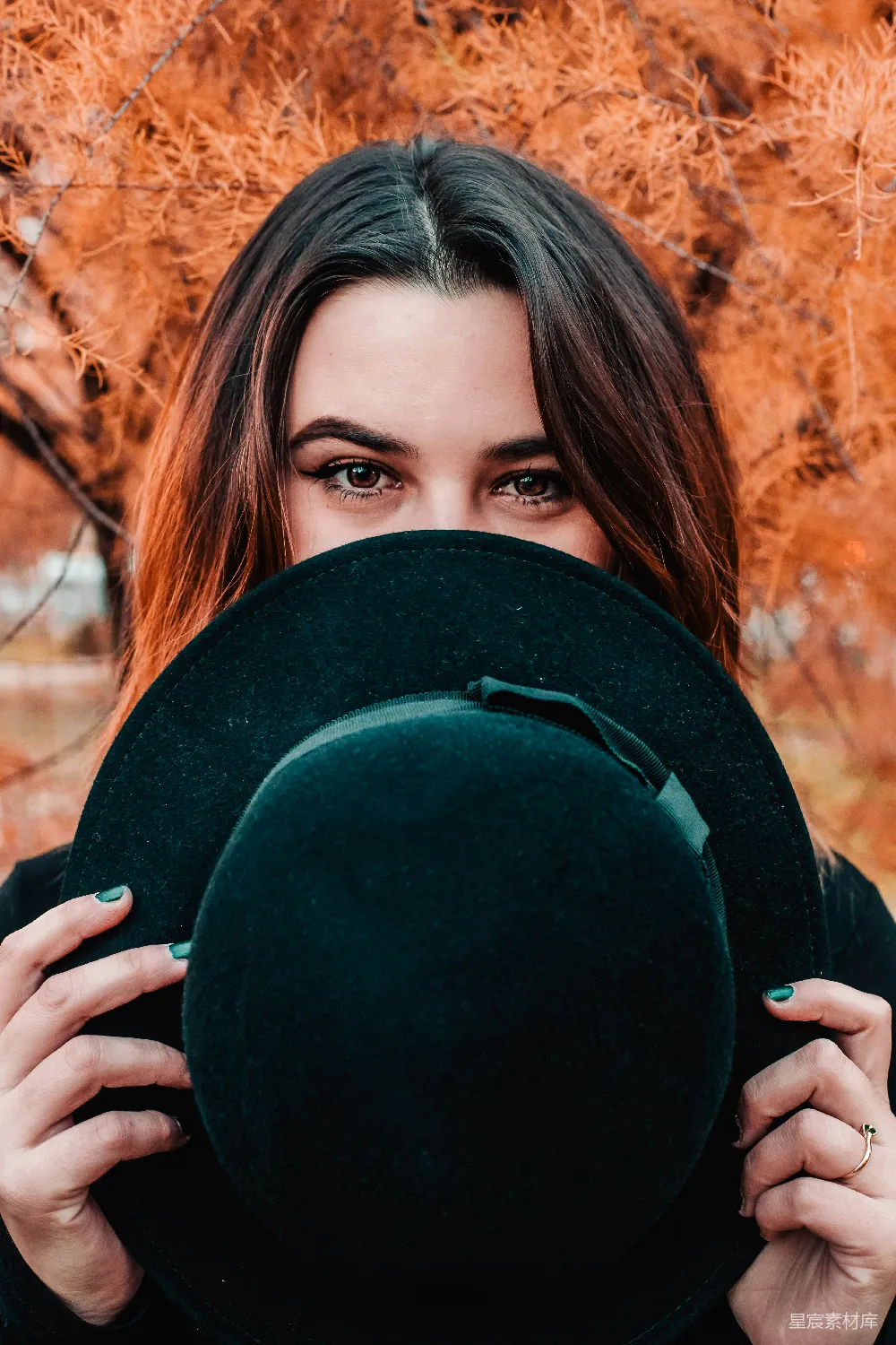高清摄影 人物 一个女人拿着一顶绿色的帽子遮在面前。