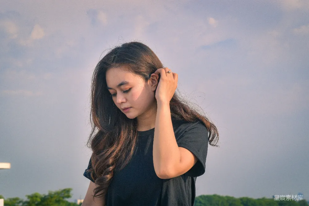高清摄影  一个年轻女子在风中梳理着头发。