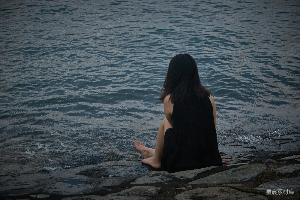 高清摄影  一位女士坐在水边的边缘。