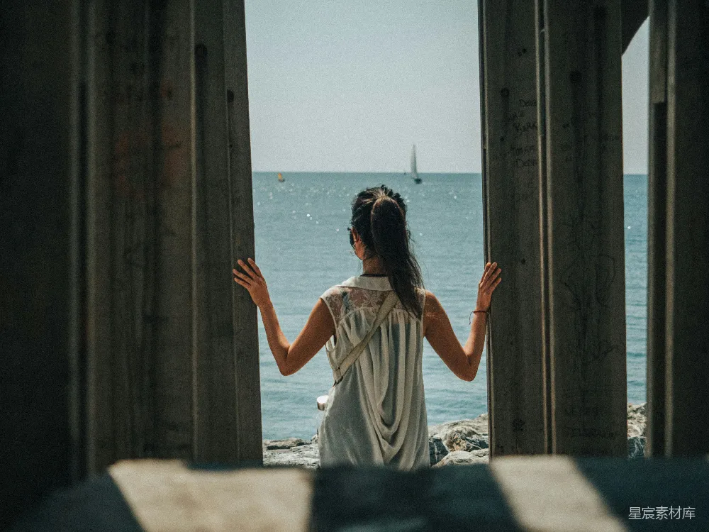 高清摄影 人物 白天，一位穿着白色连衣裙的女子站在海滩上。