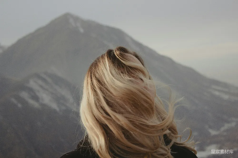 高清摄影  一个金发女人正看着一座山。