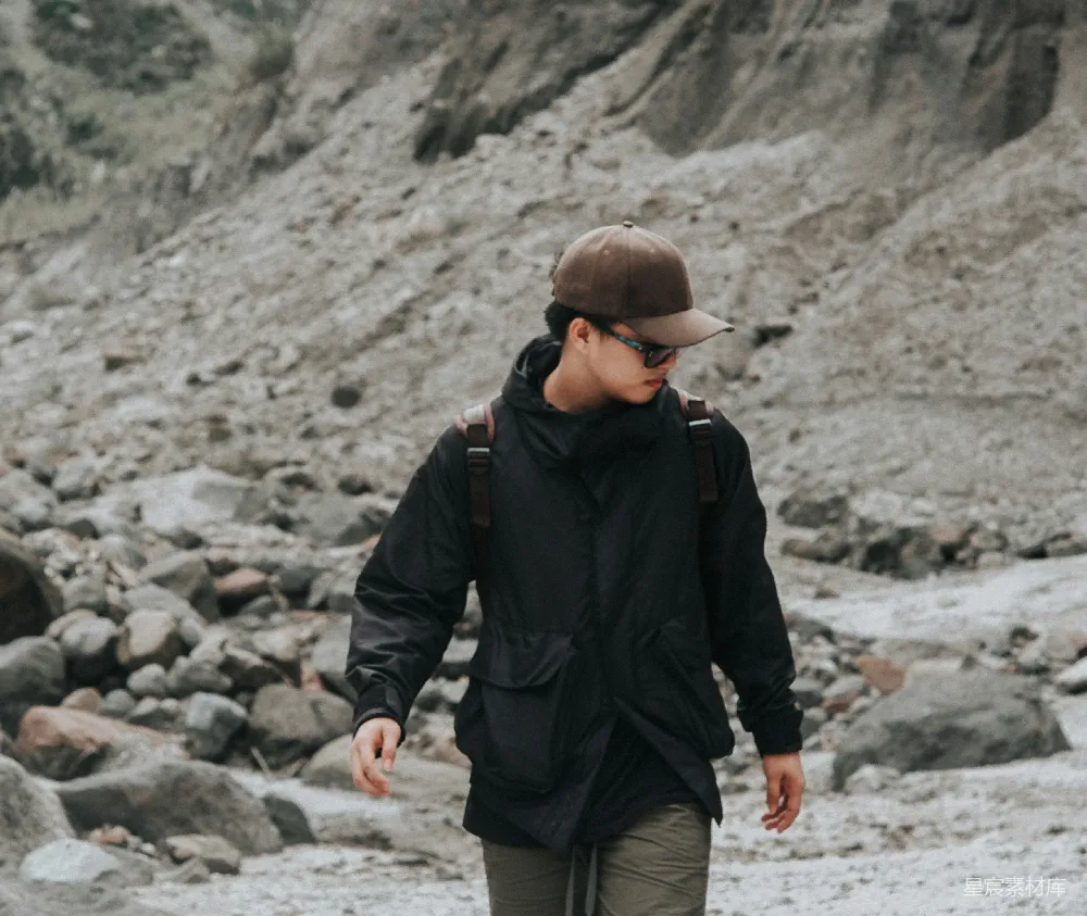 高清摄影  一个戴着帽子的男人在岩石海滩上行走