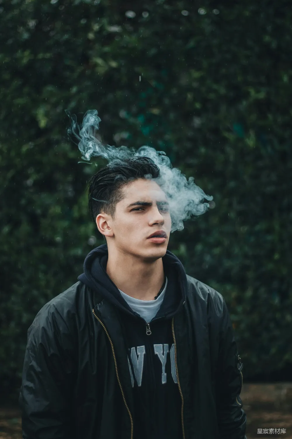高清摄影  男人在绿叶树旁吸烟
