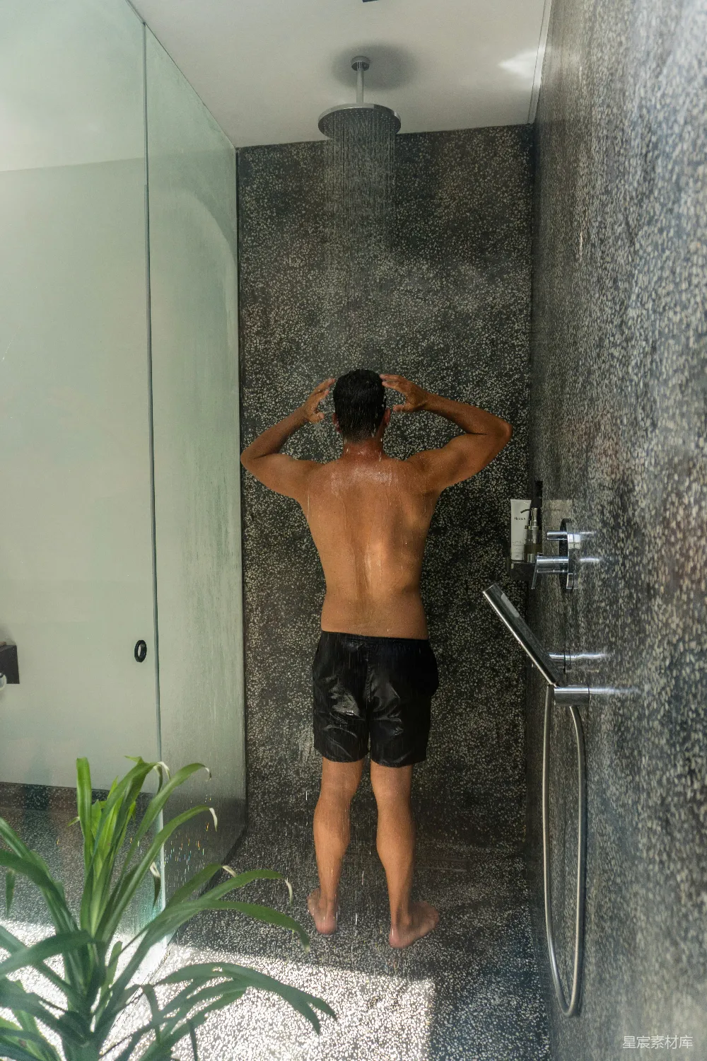 高清摄影  一个男人站在浴室的淋浴前。