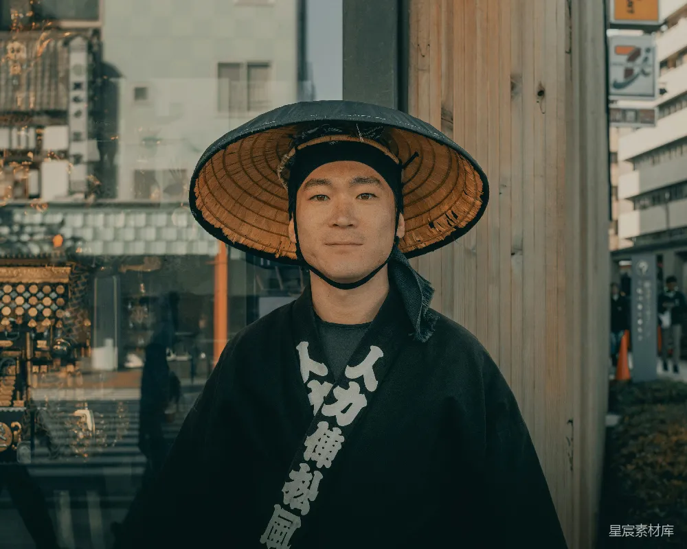 高清摄影 人物 穿着黑色外套的女人戴着棕色编织的帽子，站在白天的棕色木墙旁边。