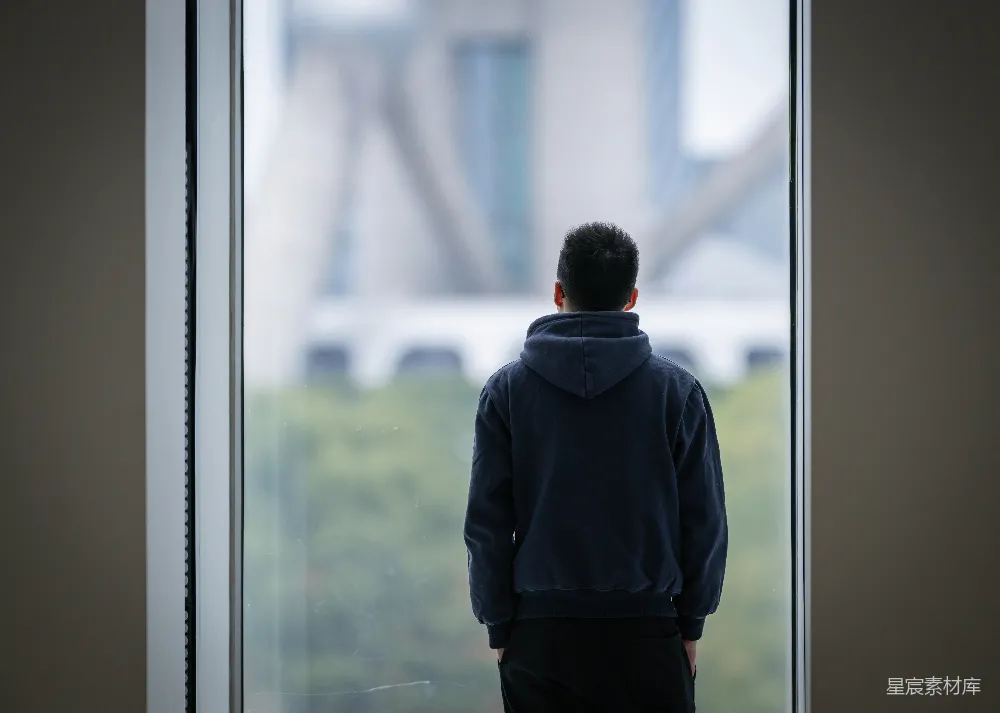 高清摄影 人物 一个男人站在窗前，向窗外看去。