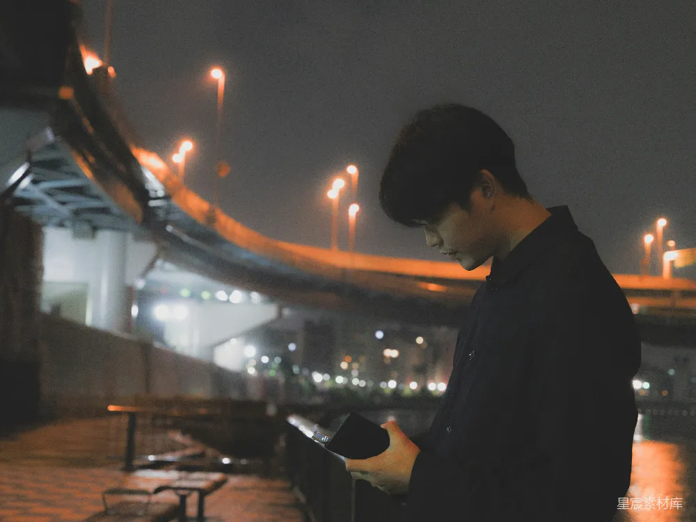 高清摄影  一个男人在晚上看着手机。