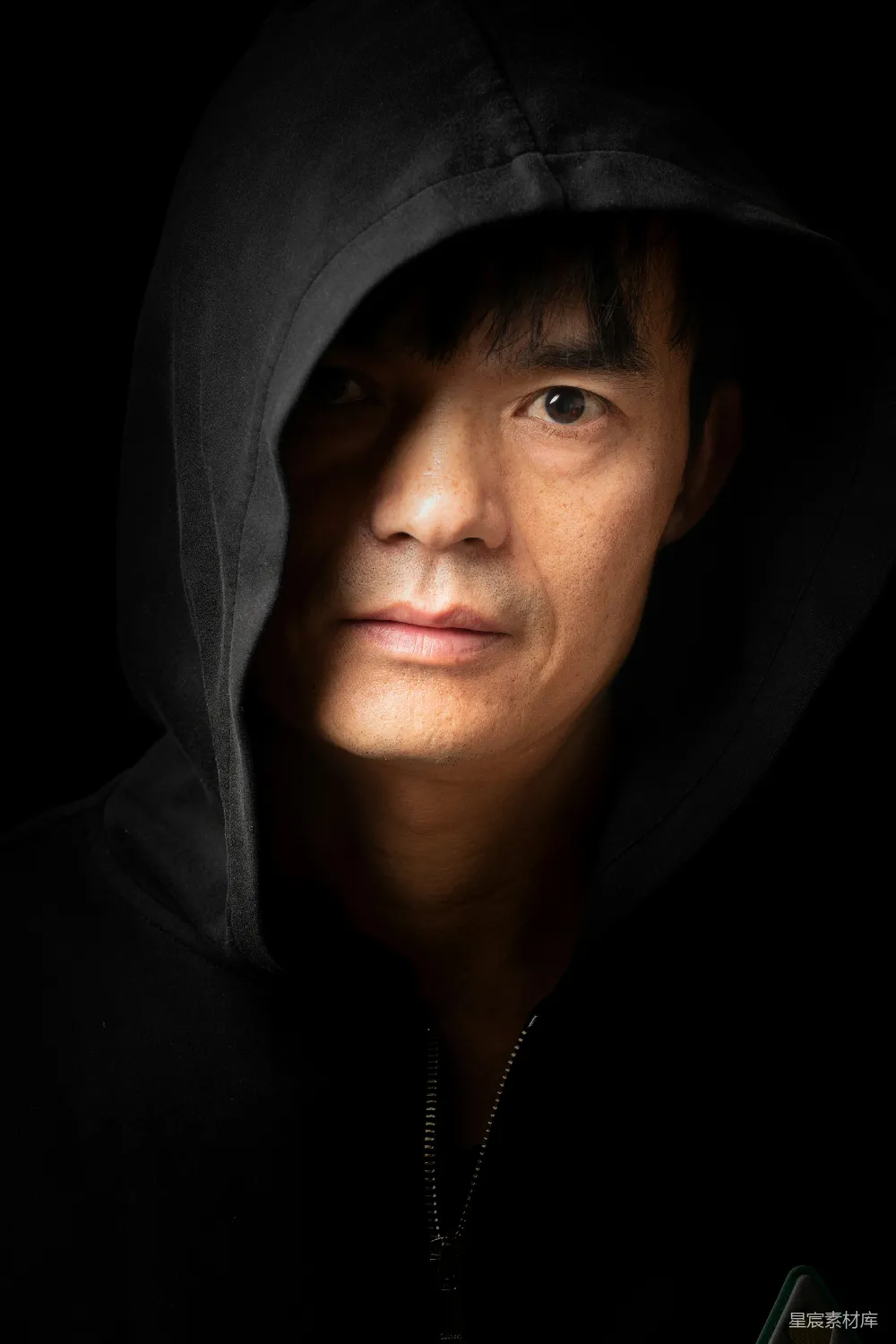 高清摄影  穿着深色连帽衫的男人，脸上有阴影。