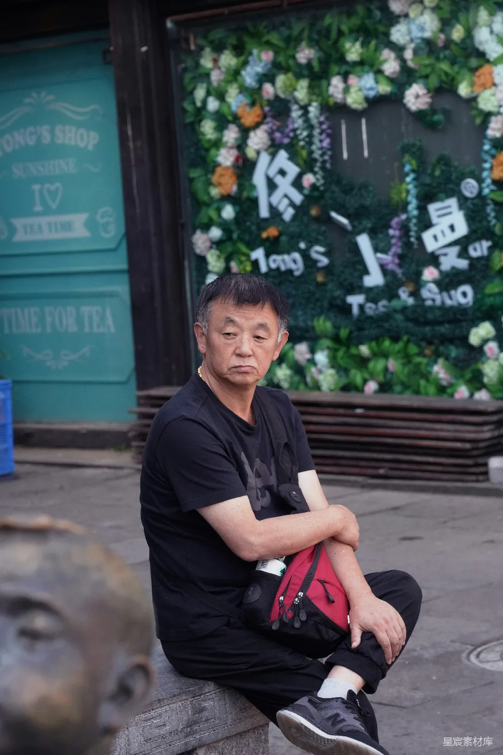 高清摄影  穿着黑色Polo衫的男子坐在棕色木制长凳上，时间是白天。