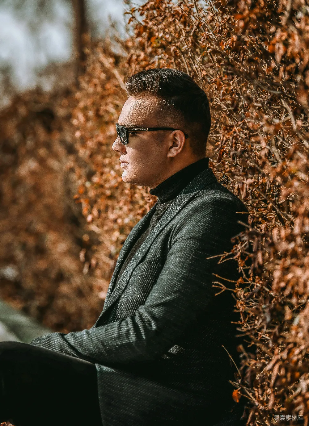 高清摄影  一个穿着西装、戴着墨镜的男人靠在墙上。