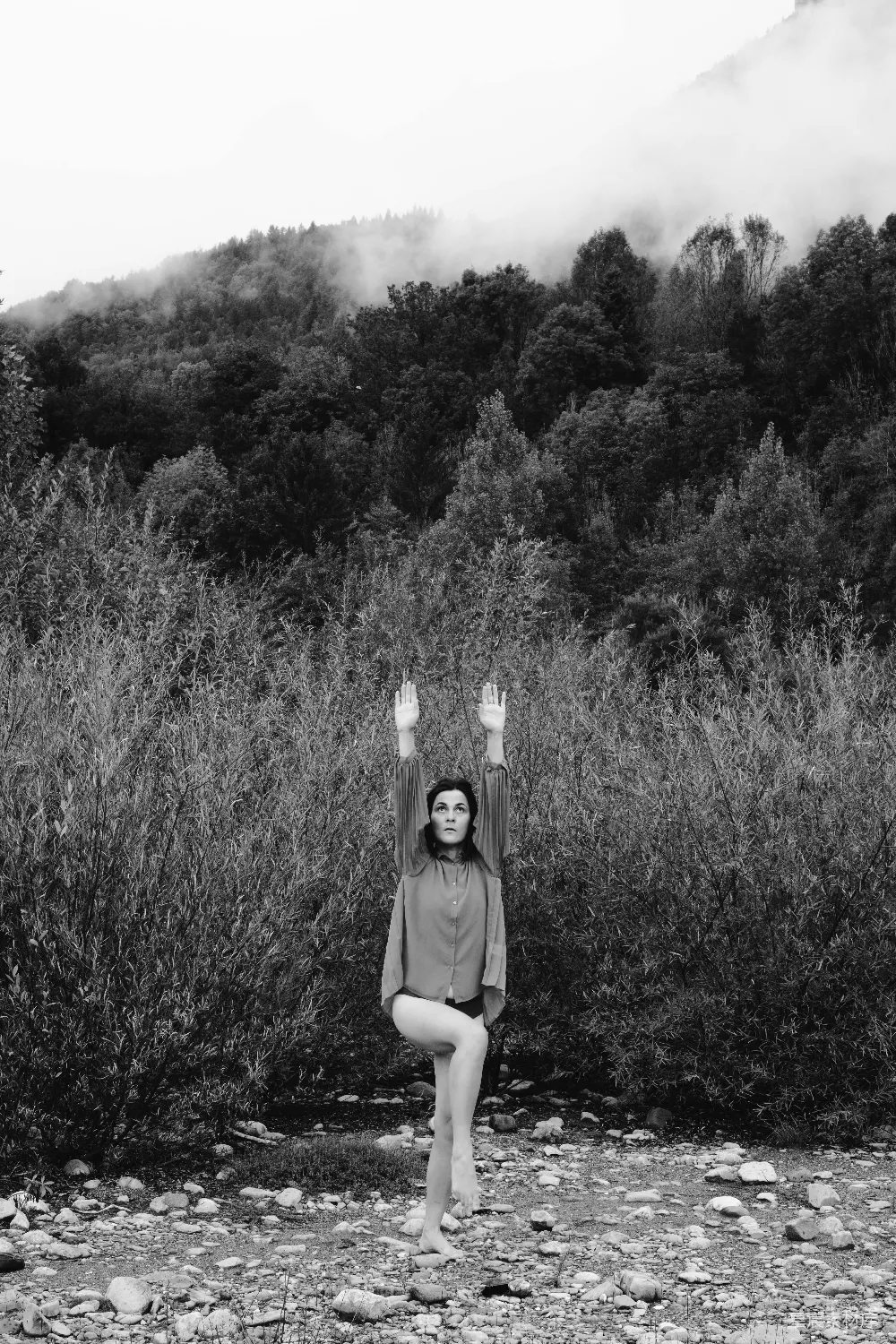 高清摄影  女人在树木和薄雾缭绕的群山中练习瑜伽。