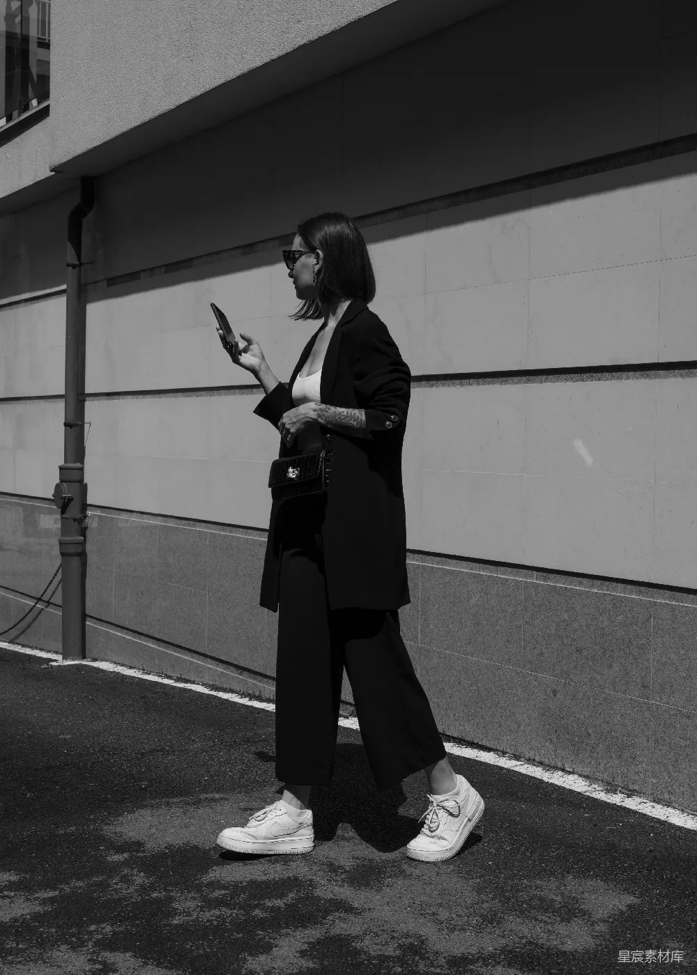 高清摄影 人物 一个女人在街上边走边拿着手机。