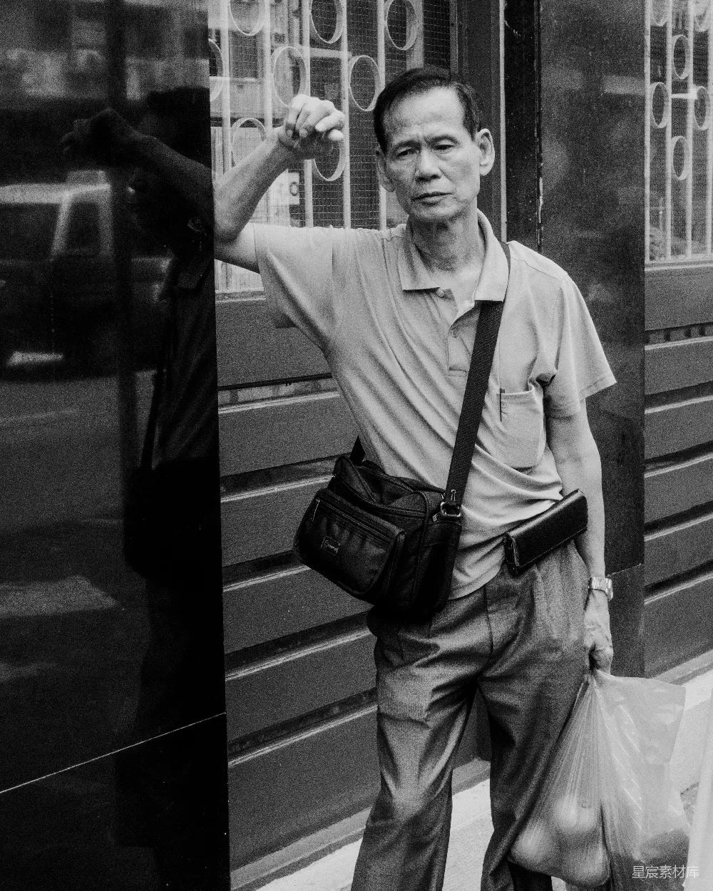 高清摄影 旅行 人物 一个男人手里拿着一个包，站在一栋建筑旁边。