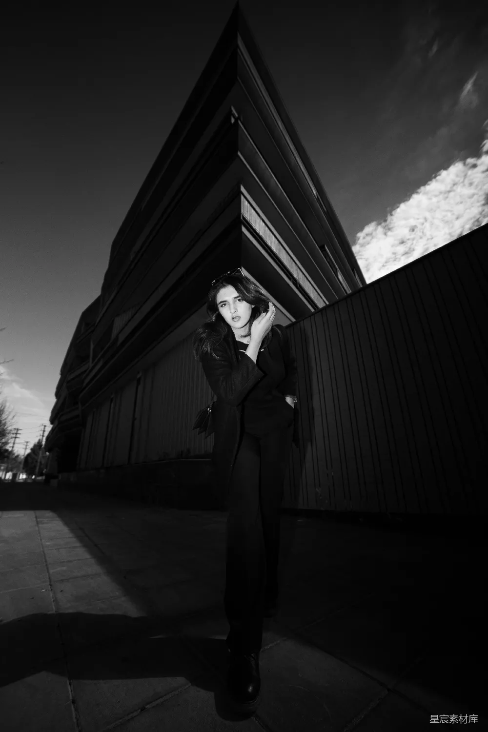 高清摄影  一个女人站在建筑物前的人行道上。