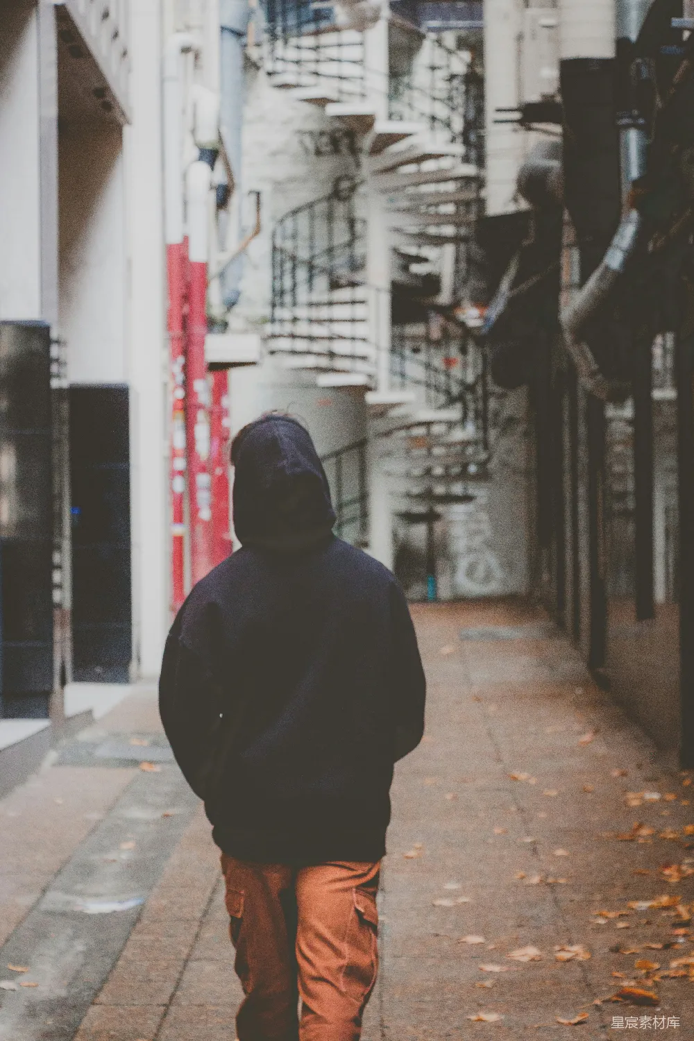 高清摄影  一个男人沿着人行道走过，旁边有一座高楼。