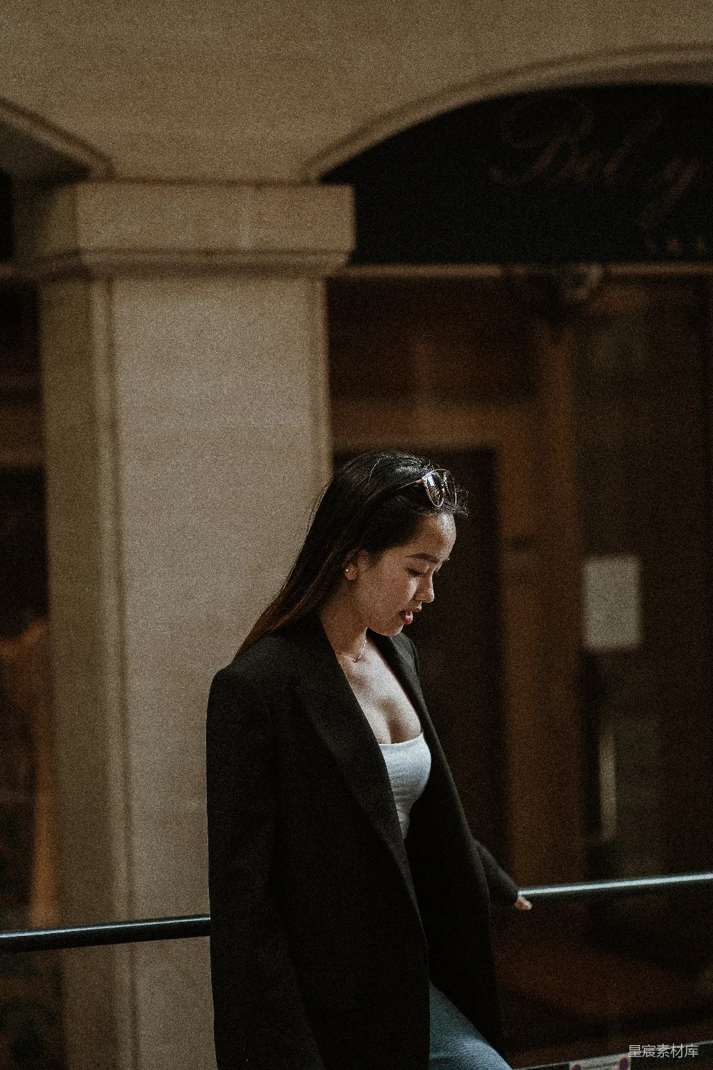高清摄影  穿着黑色西装外套的女性站在白天的棕色混凝土建筑附近。