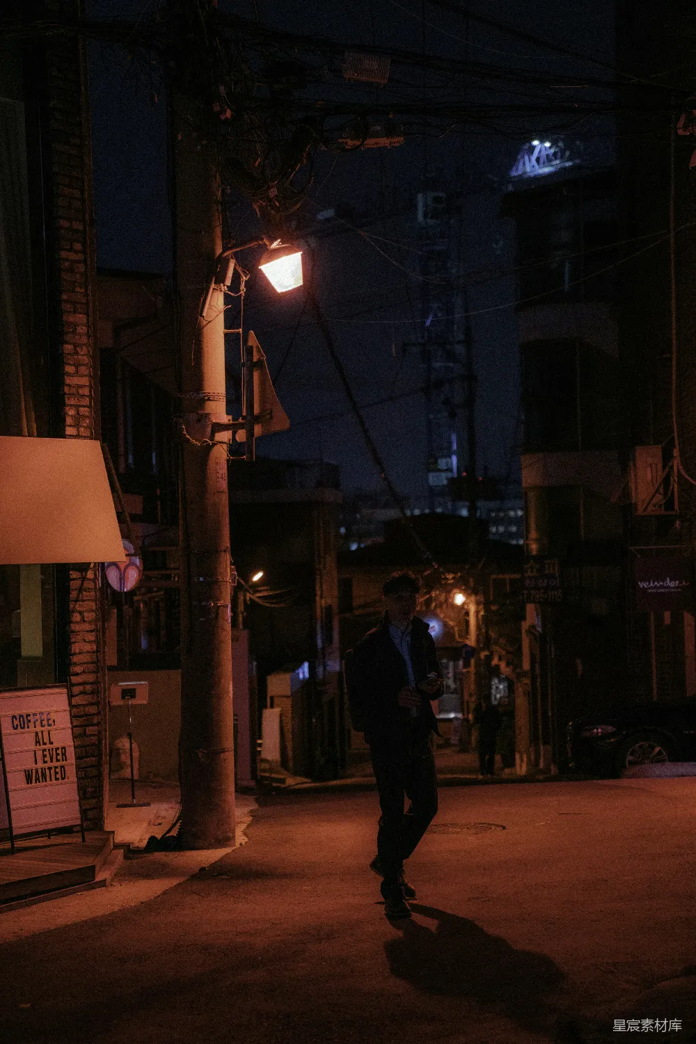 高清摄影  穿着黑色夹克和裤子的男人夜晚走在街上。